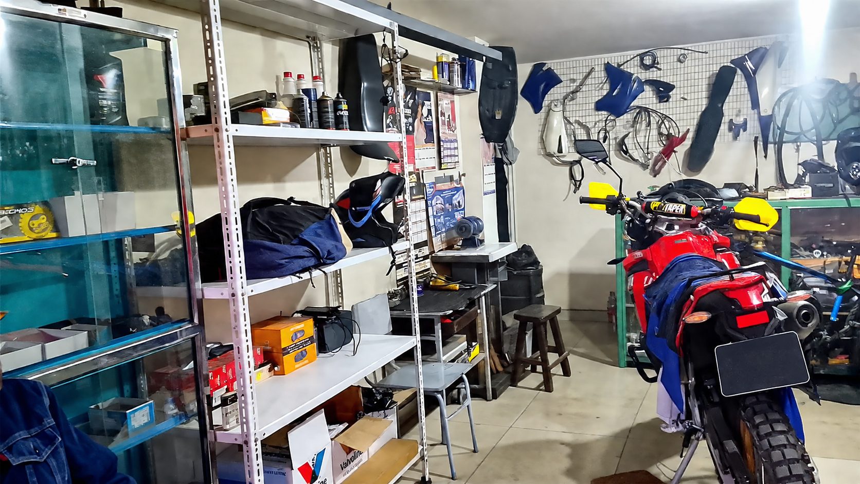 Taller eléctrico de motos en Ibarra, Ecuador: estantes con repuestos, aceites y accesorios, y una moto en revisión